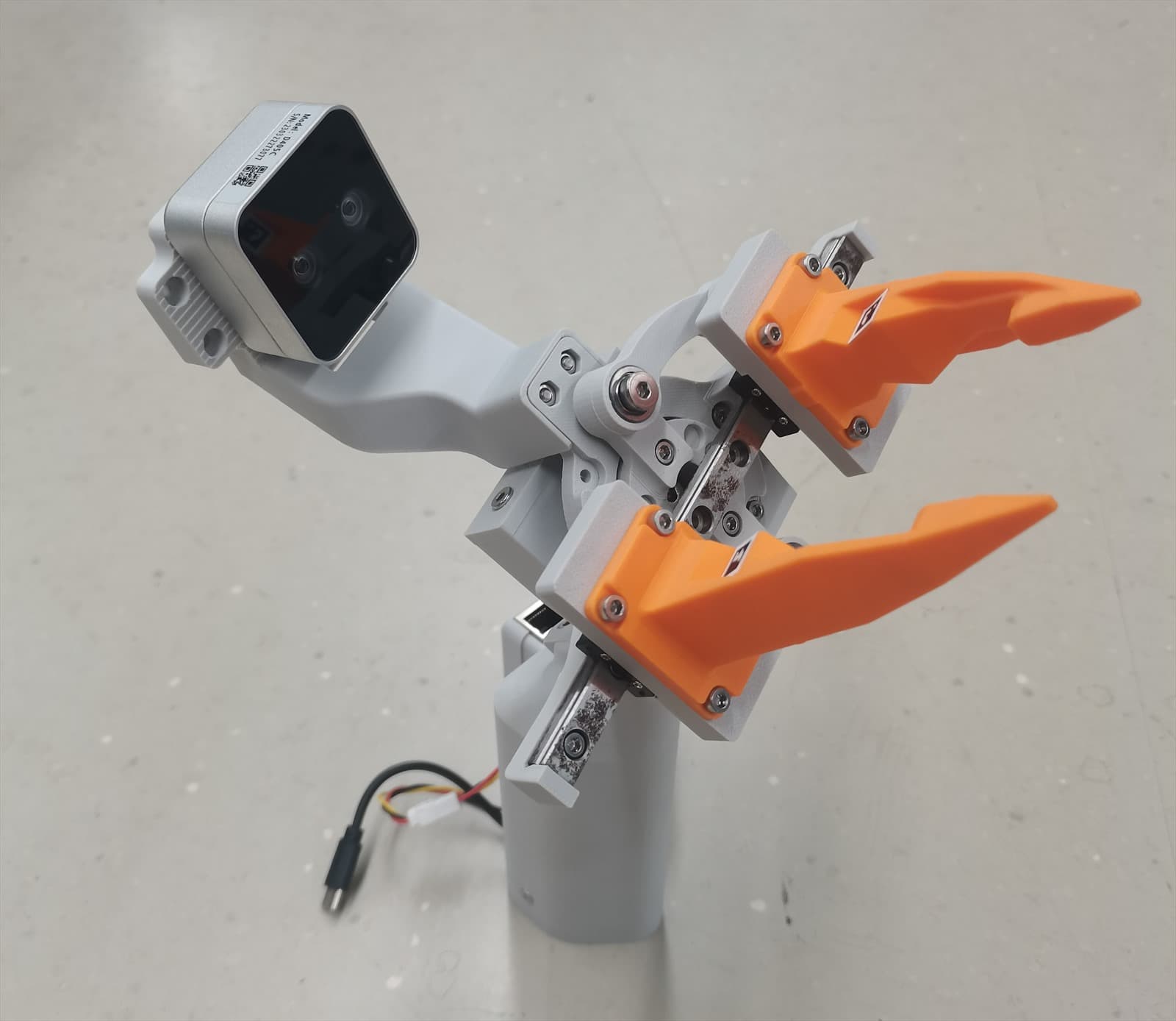 A motor-mounted SROI gripper with orange fingers and a camera mount.