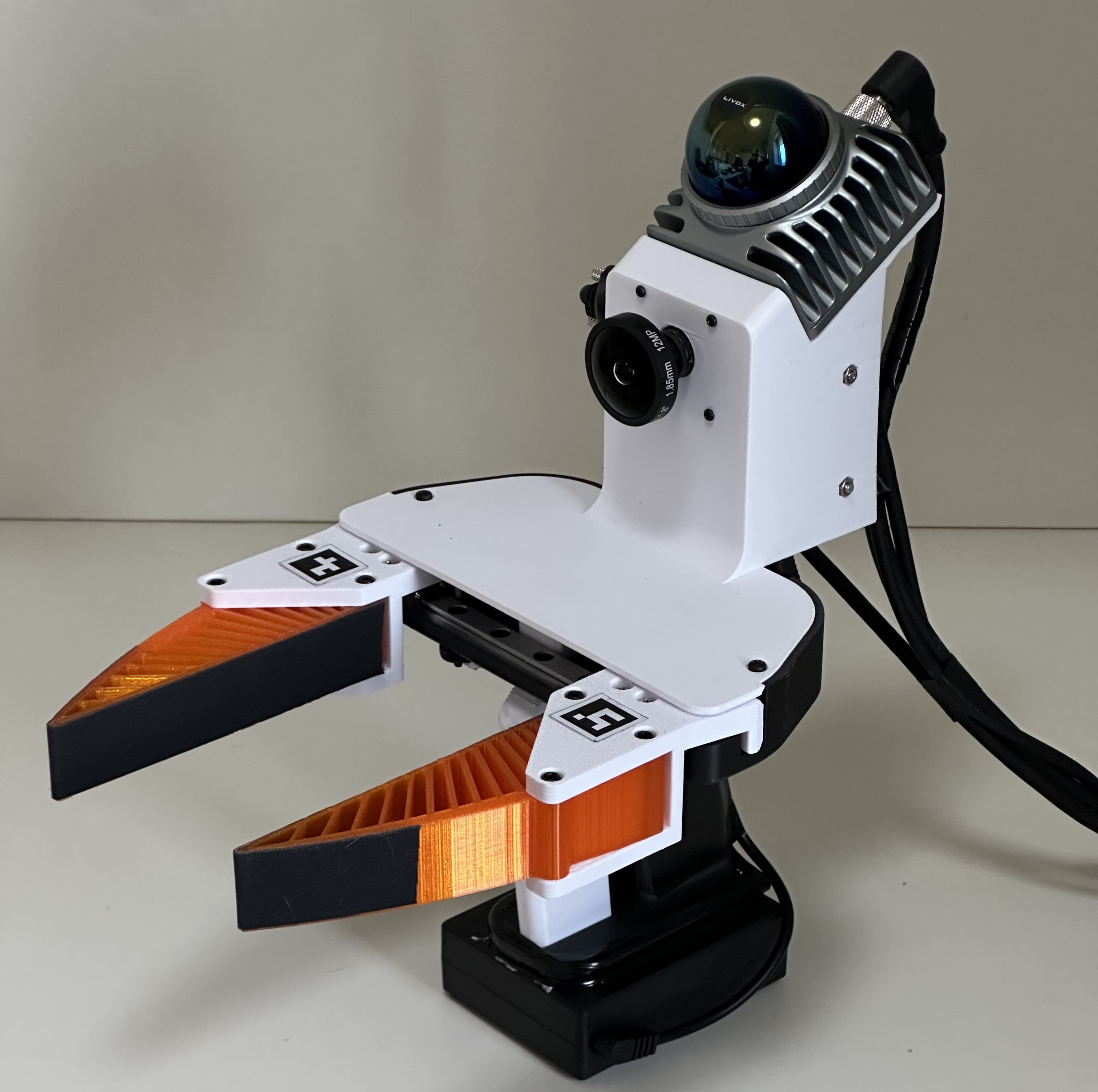 A handheld UMI-3D gripper with orange fingers, a camera and a LiDAR, photographed against a plain background.