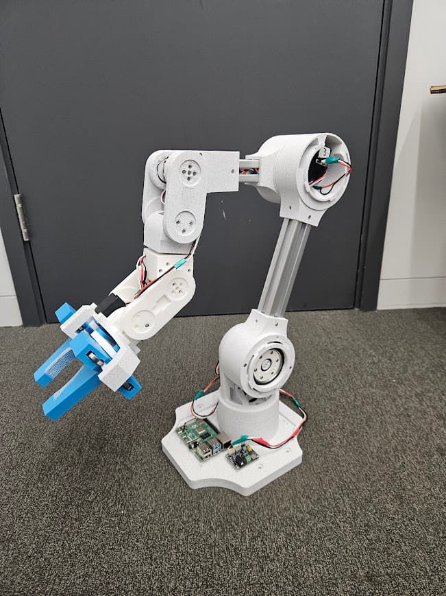 A white robotic arm with a blue gripper mounted on a base.