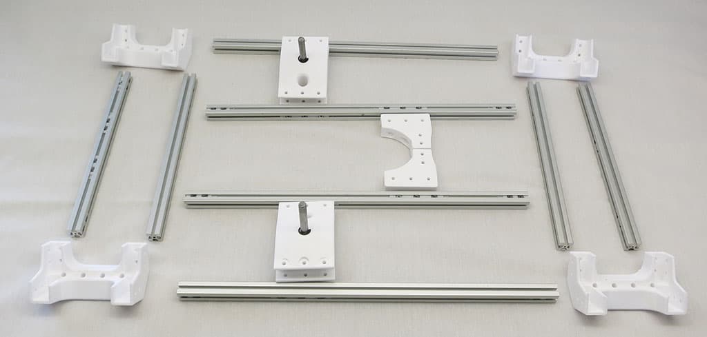 Rover frame components, including printed corner parts and aluminum extrusions, arranged for assembly.