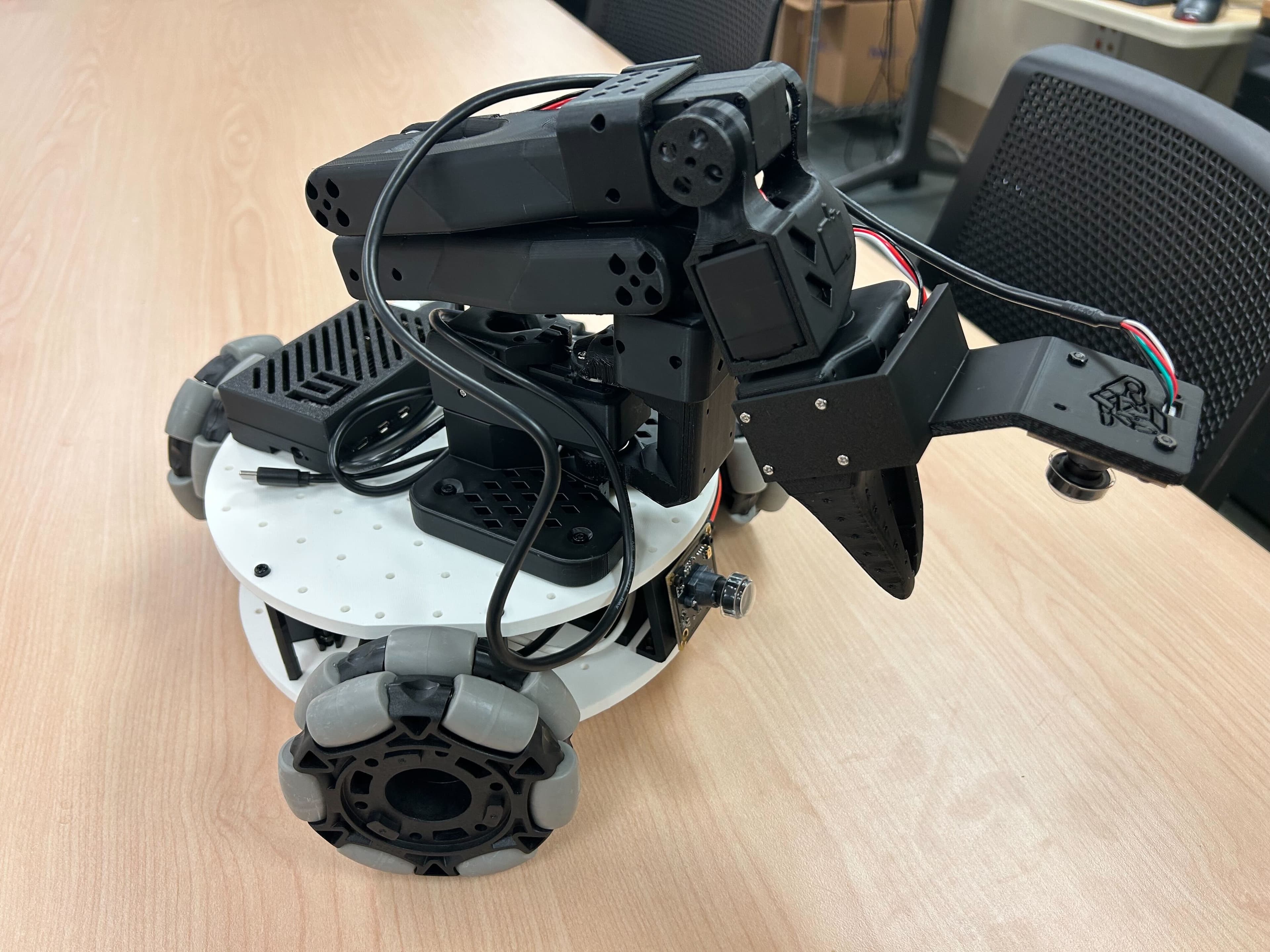 A physical LeKiwi mobile manipulator with an arm and three omni wheels.