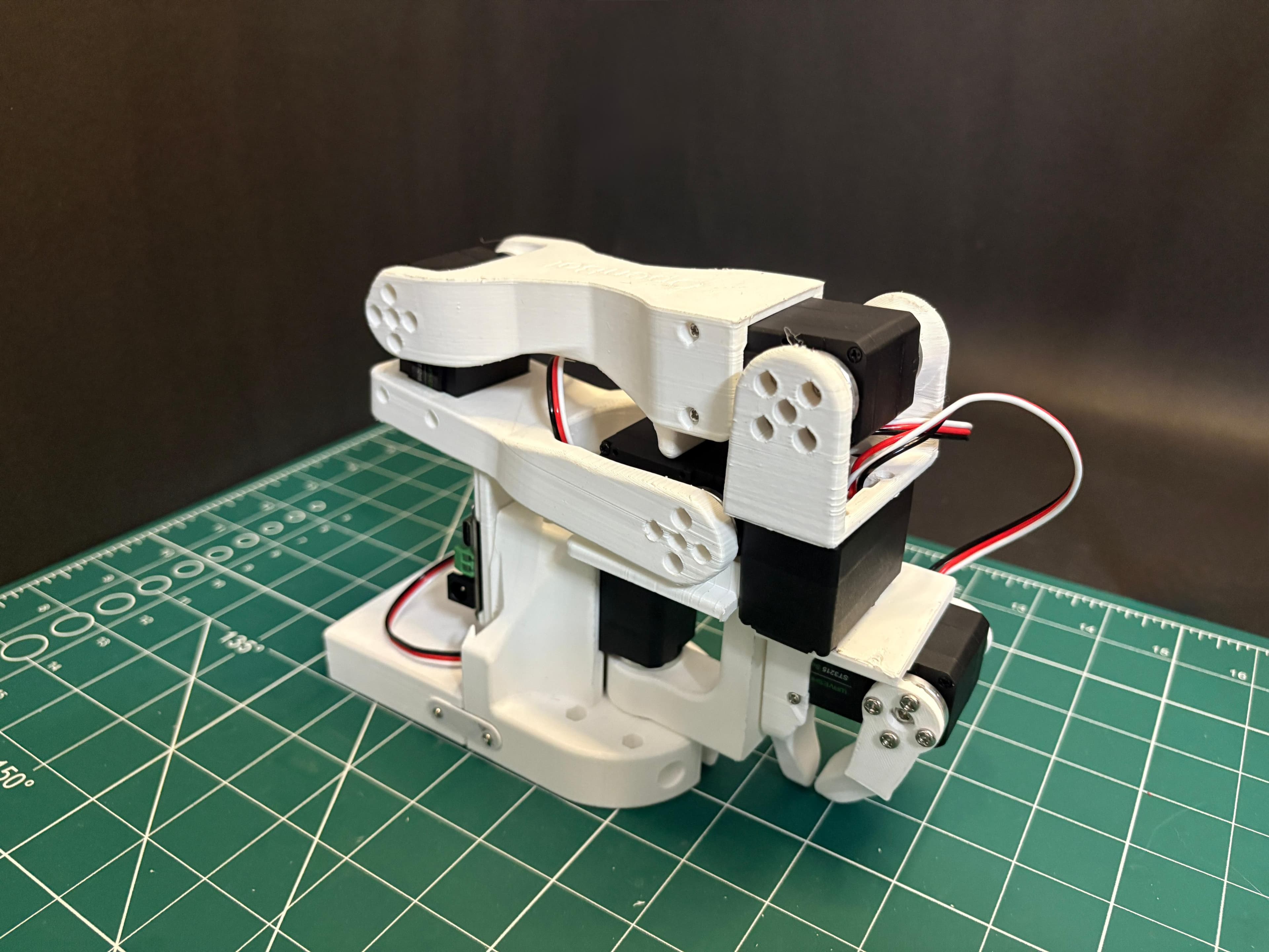A white Giraffe robotic arm on a cutting mat.