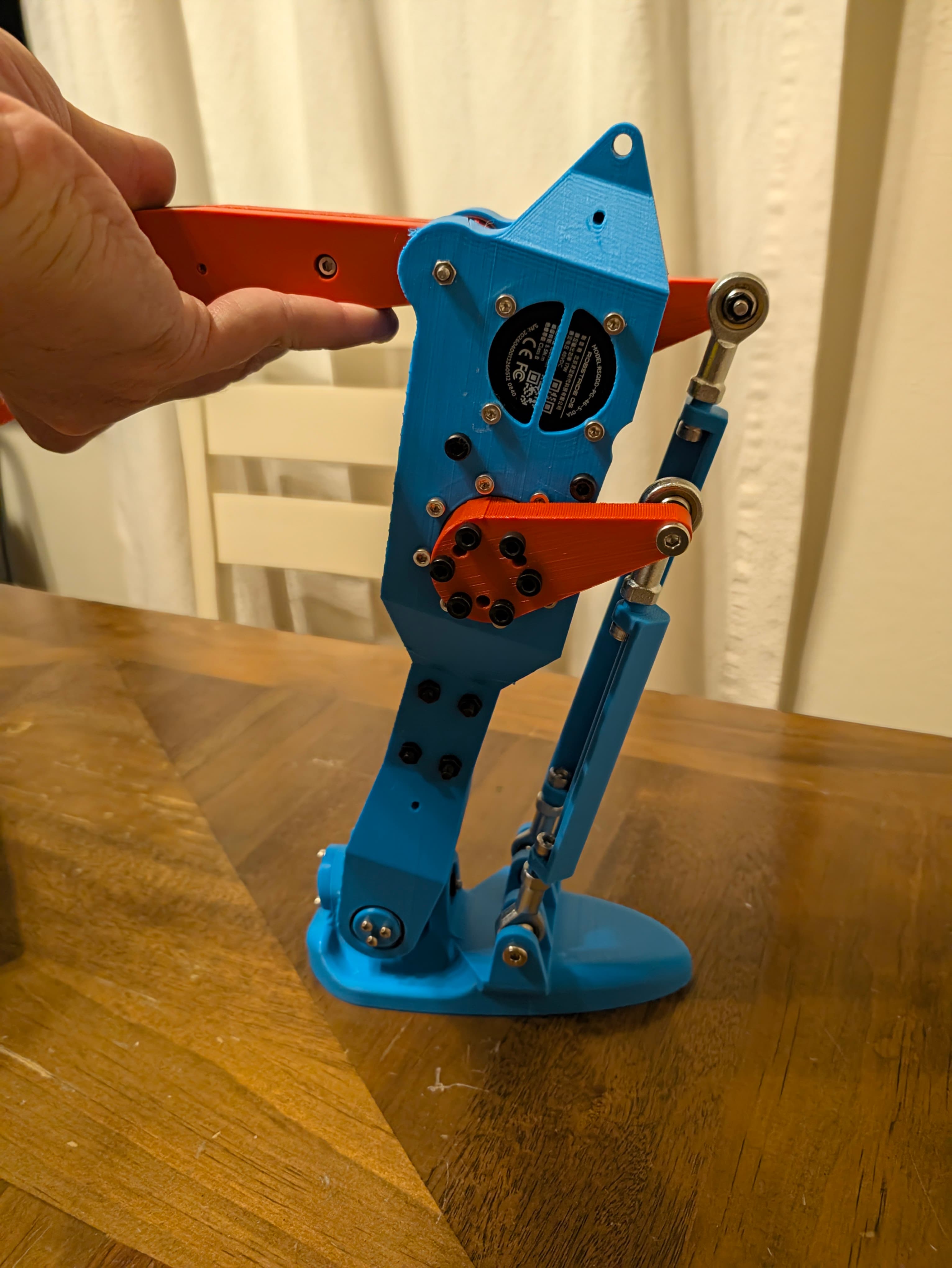 A blue and orange assembled lower-leg section with an actuator and ankle linkage.
