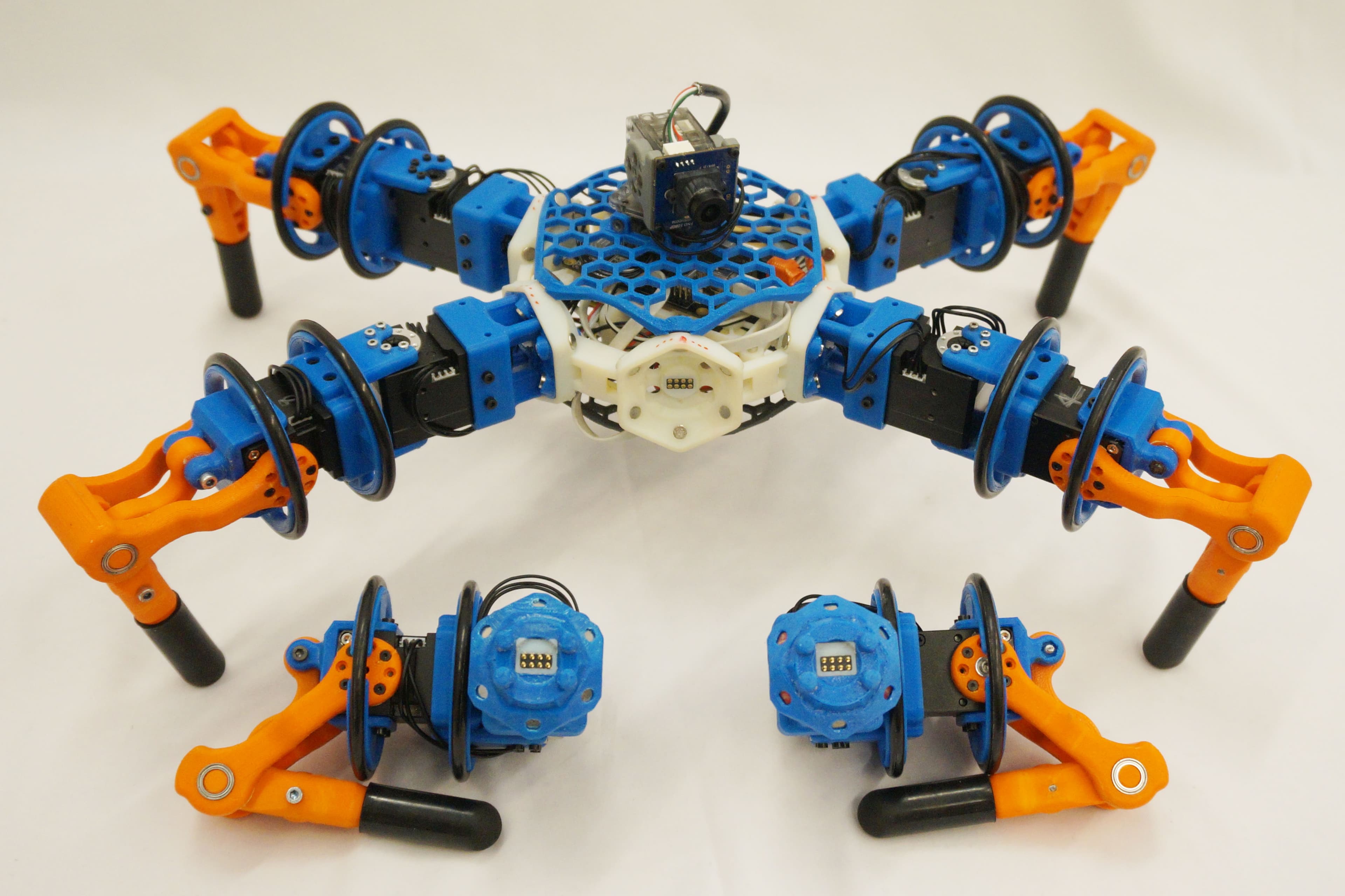 A physical Snapbot robot with a blue-and-white body and orange feet, alongside several detached leg modules.